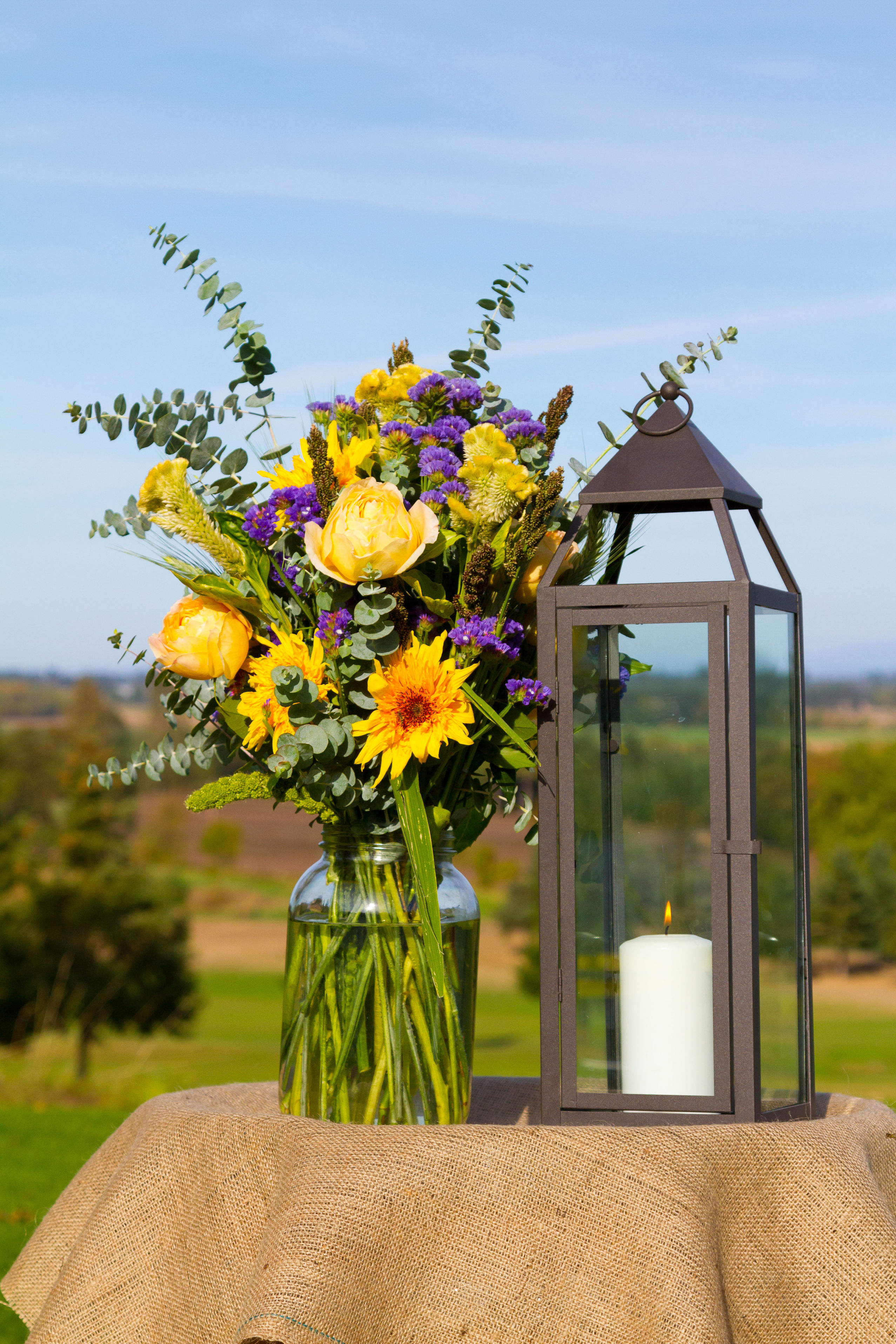 bouquet jaune et violet dans bocal avec une lanterne